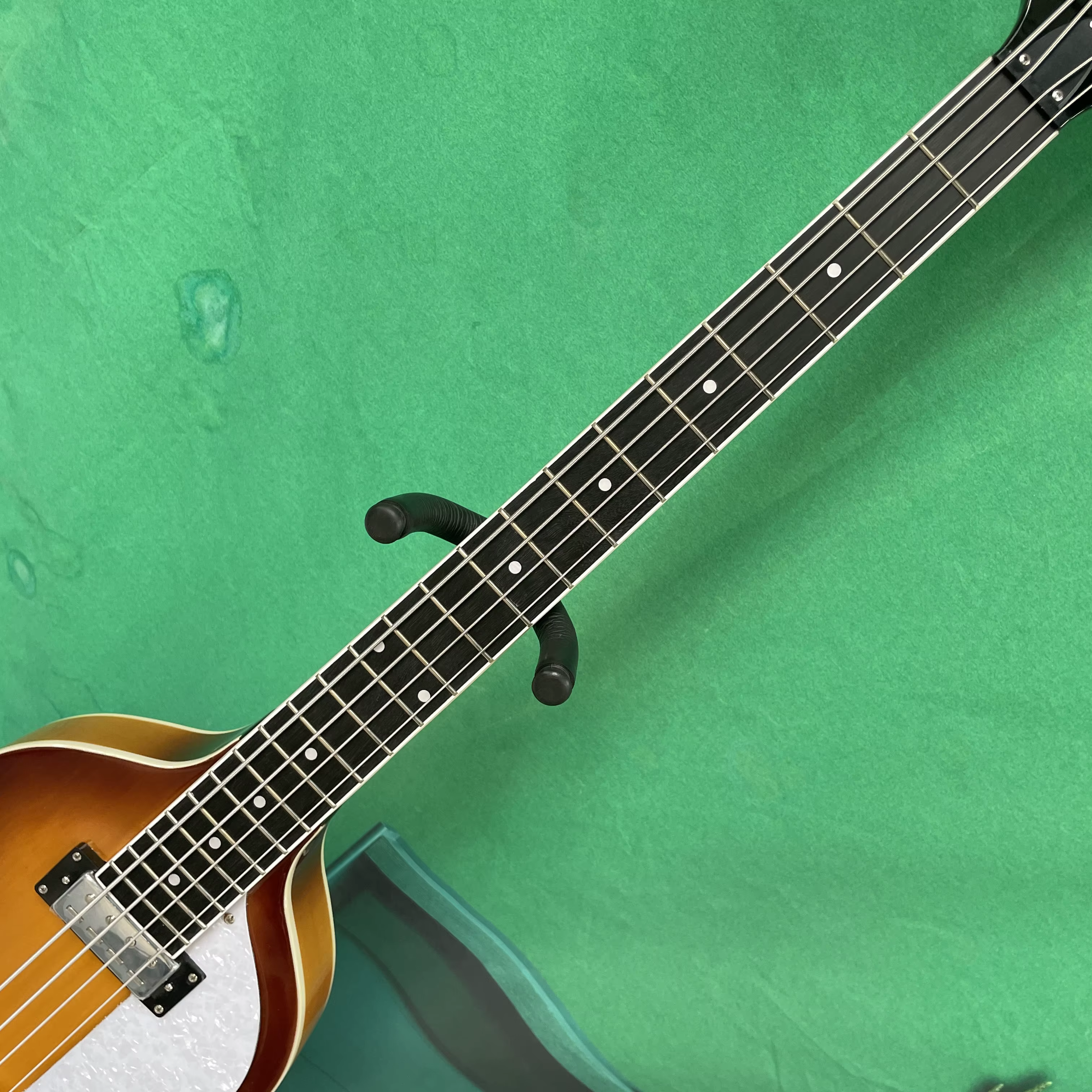 Guitare basse électrique à 4 cordes, corps de style violon, pickguard blanc, quincaillerie argentée, idéale pour les guitaristes débutants.