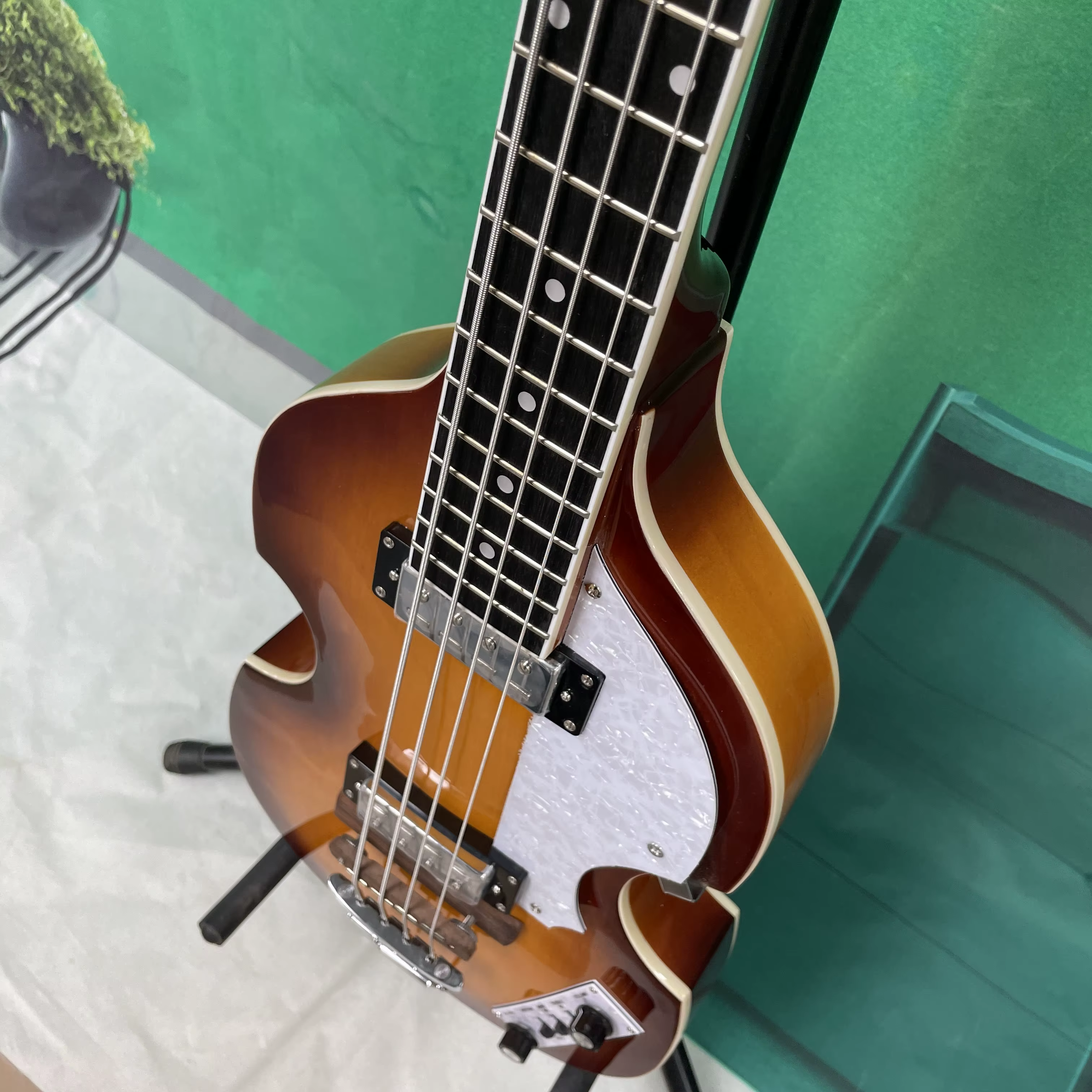 Guitare basse électrique à 4 cordes, corps de style violon, pickguard blanc, quincaillerie argentée, idéale pour les guitaristes débutants.