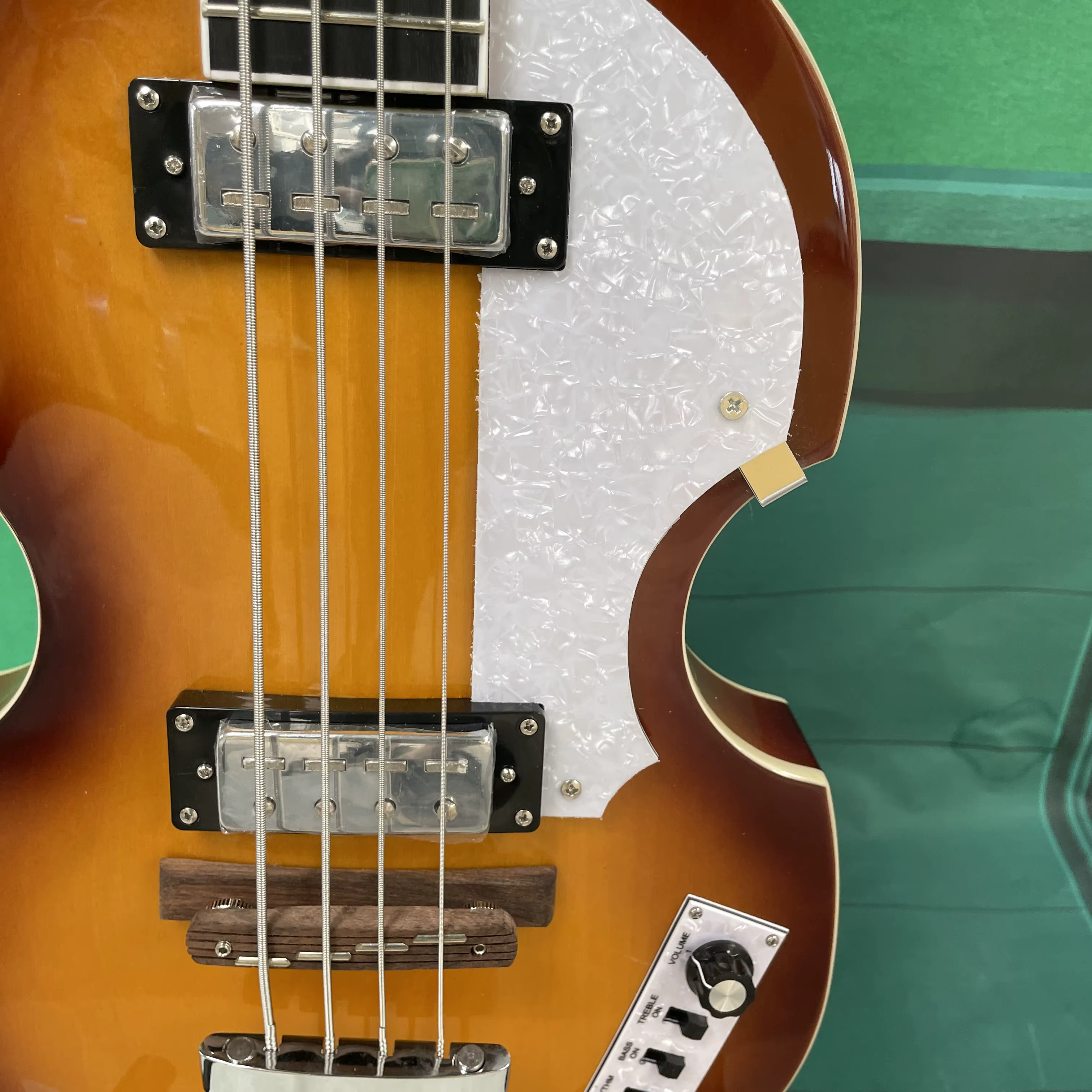 Guitare basse électrique à 4 cordes, corps de style violon, pickguard blanc, quincaillerie argentée, idéale pour les guitaristes débutants.